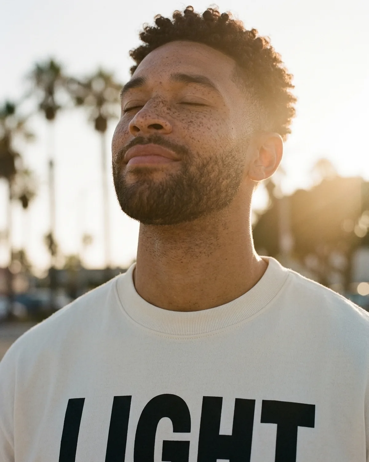 Marcus lifting his freckled face to the late sun, eyes closed, in the Loud and Proud tee