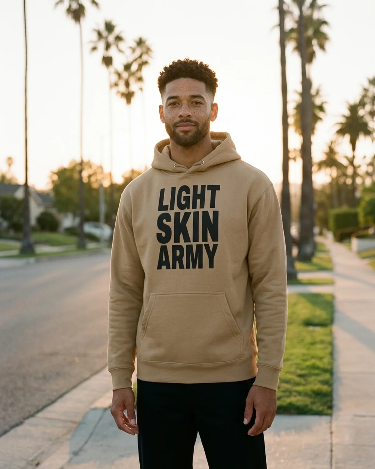 Marcus wearing the Khaki Loud and Proud Hoodie on a palm-lined View Park street at golden hour