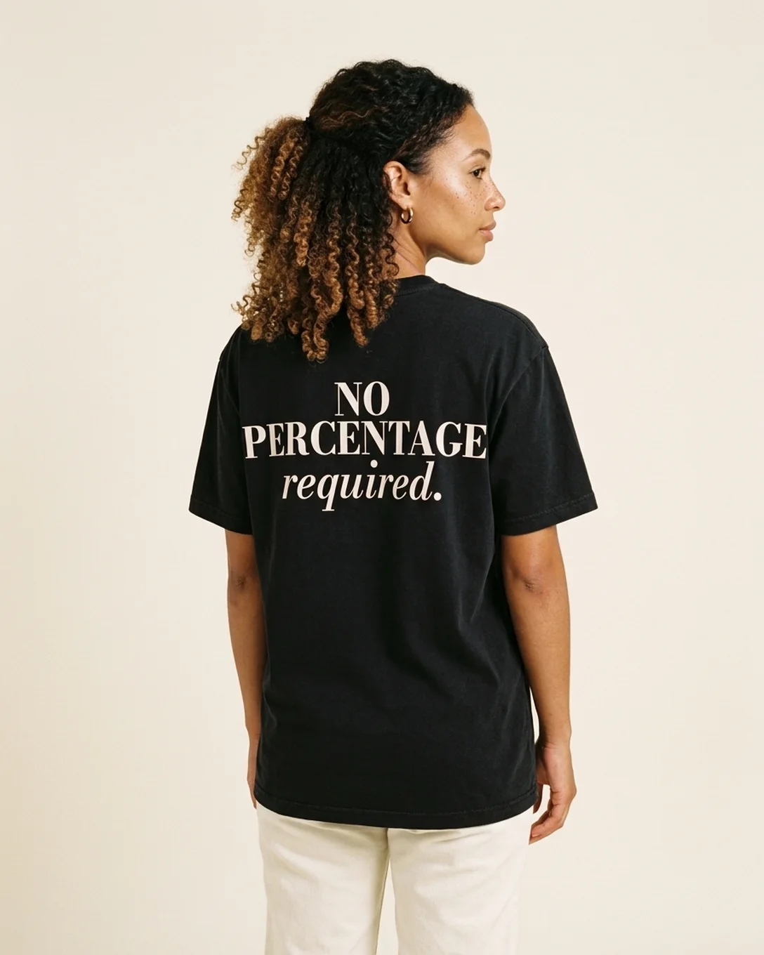 Back view of a model wearing the No Percentage tee in Black, reading NO PERCENTAGE required.