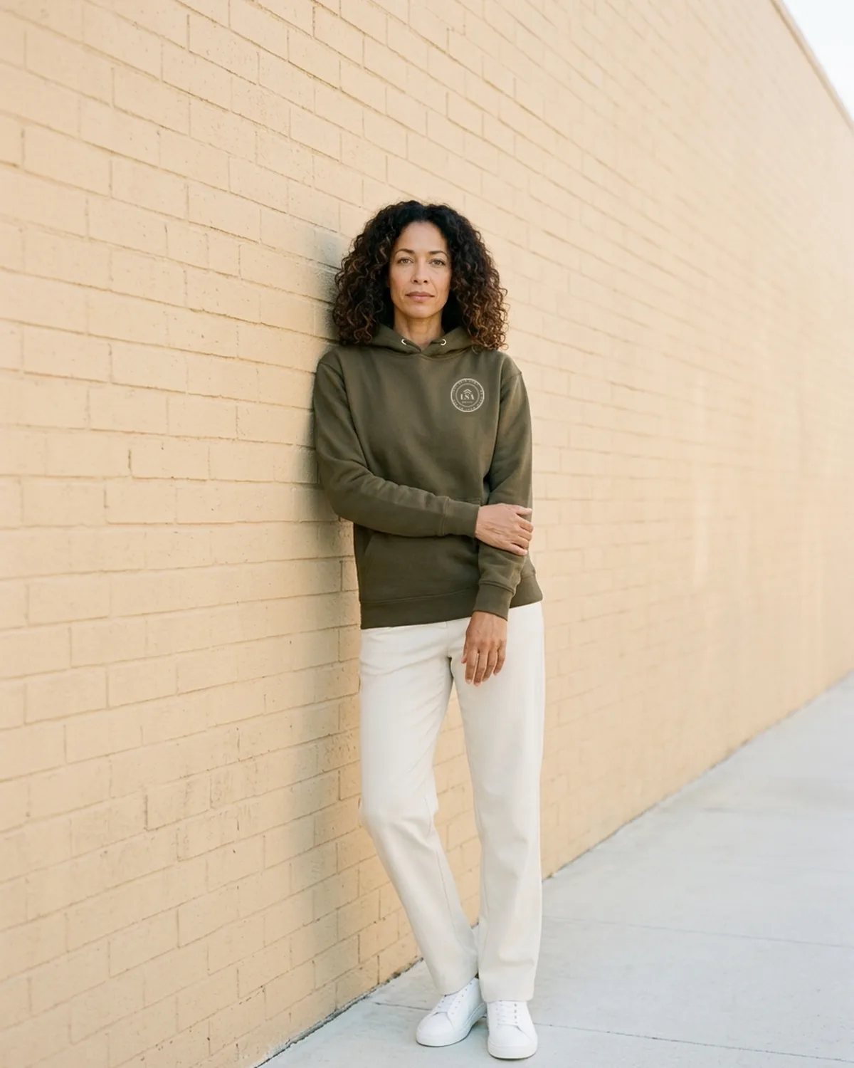 Simone wearing the Military Green Unit Patch Hoodie against an Arts District brick wall